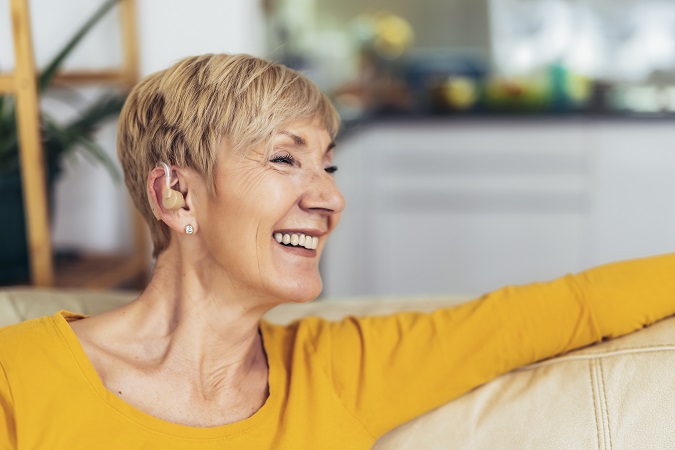 Mature woman with hearing aid indoors smiling